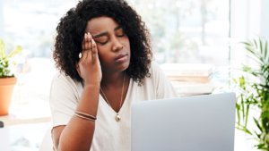 Black women in front of laptop holding her head feeling exhausted