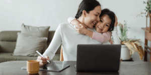 A parent and child using a laptop at home.